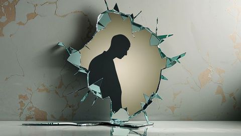 Silhouette reflected in cracked mirror with glass shards