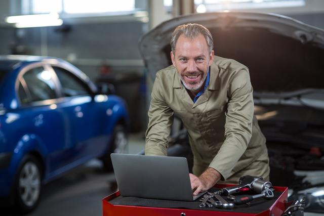 Portrait of mechanic using laptop in repair garage