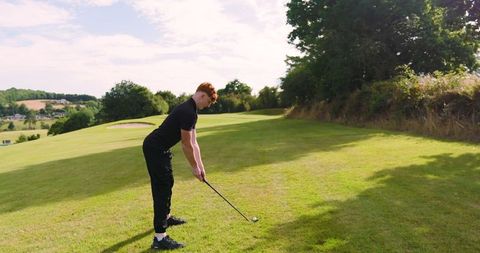 Teenage boy perfecting golf swing on sunny fairway