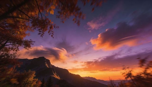 Mountain ridge glowing at vivid sunset with autumn leaves framing twilight sky