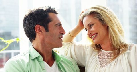 Romantic Couple Embracing and Smiling in Sunlit Living Room
