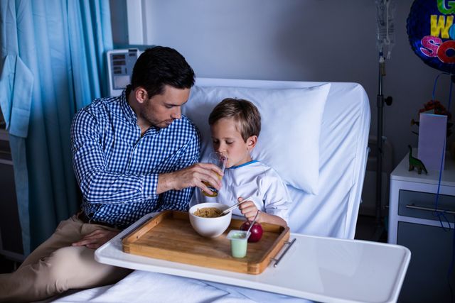 Father feeding breakfast to his son at hospital