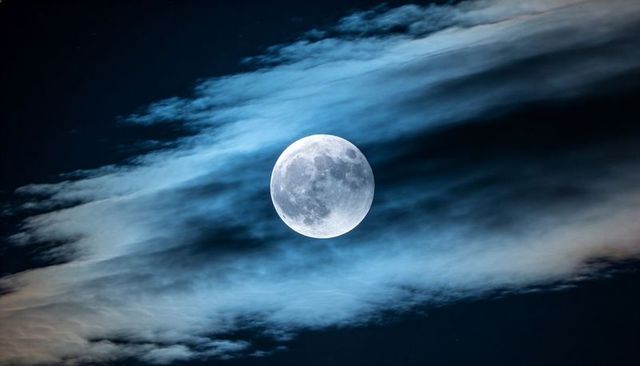 Glowing Full Moon with Wispy Clouds Over Deep Blue Night Sky, Lunar Celestial Scene
