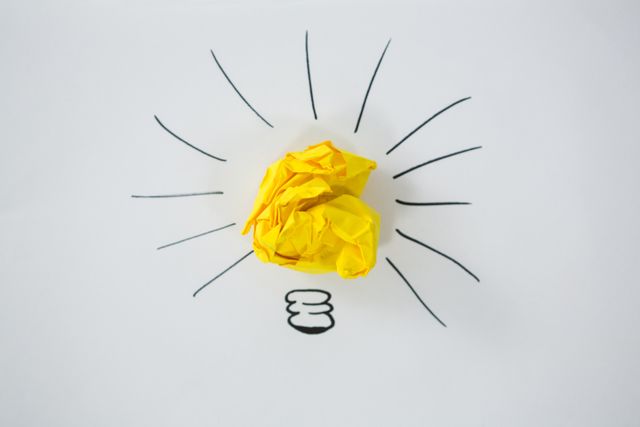 Conceptual image of light bulb drawn around crumbled Yellow paper