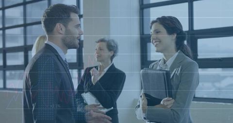 Business professionals networking and reviewing financial data with digital graph overlay