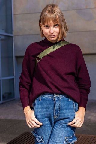 Confident woman in burgundy sweater and cargo jeans with olive crossbody strap