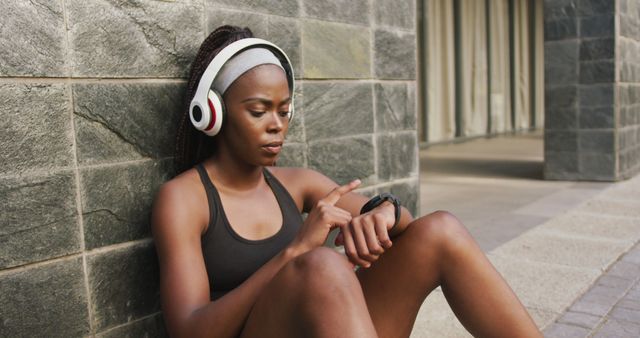 African american woman exercising outdoors wearing wireless headphone using smartwatch in the city. healthy outdoor lifestyle fitness training.