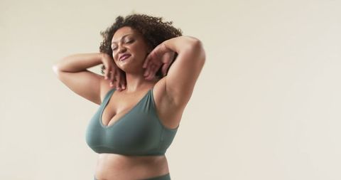 Confident curly haired woman embracing body positivity with joyful dance