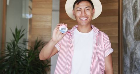 Smiling young man holding vote badge, promoting civic engagement
