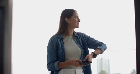 Modern Woman with Smartphone and Smartwatch Near Window