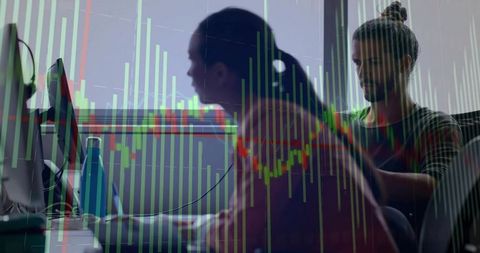 Trading team analyzing candlestick charts at desks, focused finance analysts working late