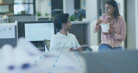 Coworkers talking over lunch in open-plan office with blue digital data overlay