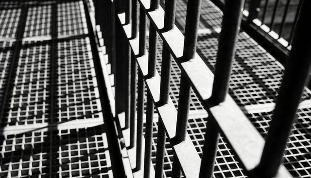 Industrial steel railing casting geometric shadows over grated catwalk and grid pattern