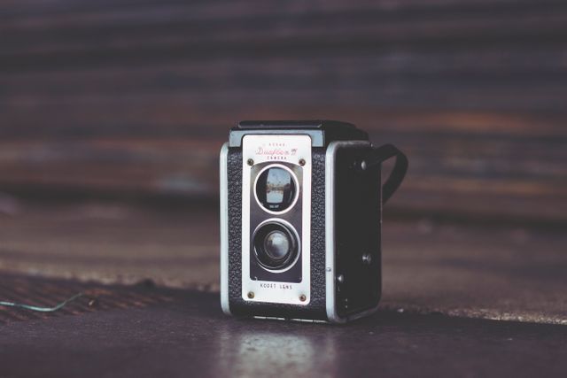 Vintage black and silver camera in dimly lit environment. Ideal for use in topics related to photography, vintage collectibles, retro aesthetics, and nostalgia. Suitable for blogs, websites, and design projects focused on photography history and classic equipment.