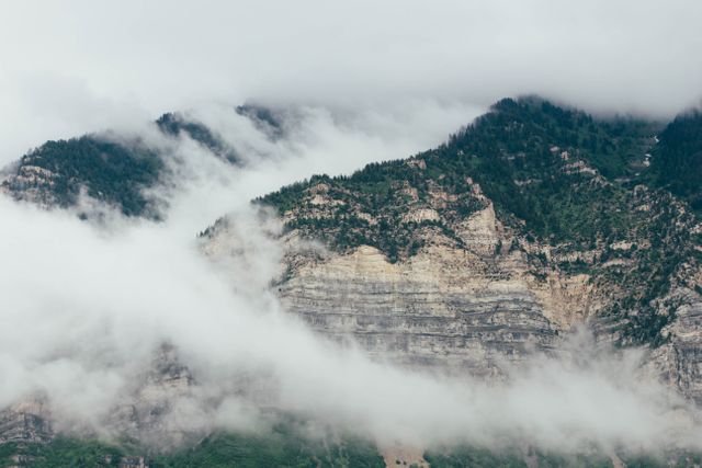 Image capturing misty mountains shrouded in dense fog. The fog creates a serene and tranquil atmosphere, ideal for use in nature projects, travel blogs, meditation content, and environmental presentations.