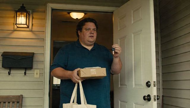 Man holding parcel and car key at suburban front door carrying tote conveying home delivery