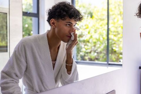 Man Practicing Skincare Routine by Bright Bathroom Vanity