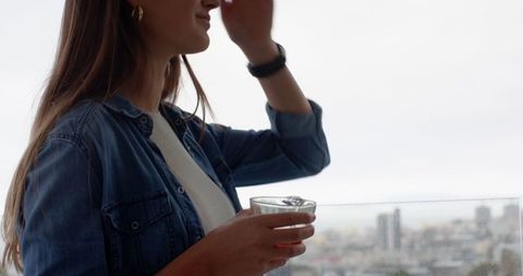 Modern Woman Enjoying Beverage with Scenic City Skyline