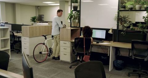Diverse Coworkers Discussing in Modern Open-Plan Office with Bicycle