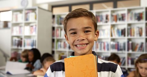 Smiling Schoolboy Holding Books in Library Setting