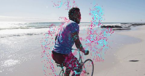 Smiling man riding bicycle along sunny beach with neon cyan-magenta particle trail