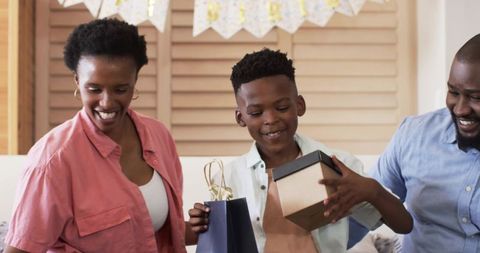 African American Family Celebrating Birthday at Home Child Opening Gift and Smiling