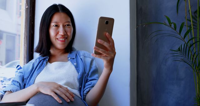 Smiling Pregnant Woman Using Smartphone at Cozy Corner - Download Free Stock Images Pikwizard.com