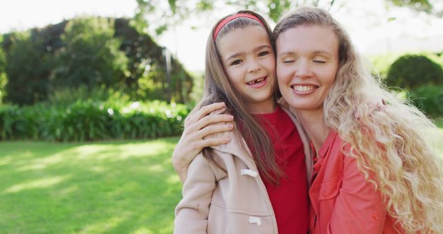 Image portrait of happy caucasian mother embracing with smiling daughter in garden. Family, domestic life and togetherness concept digitally generated image.
