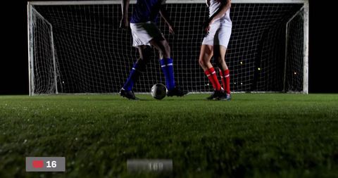 Night soccer duel under stadium lights competing for ball at goal