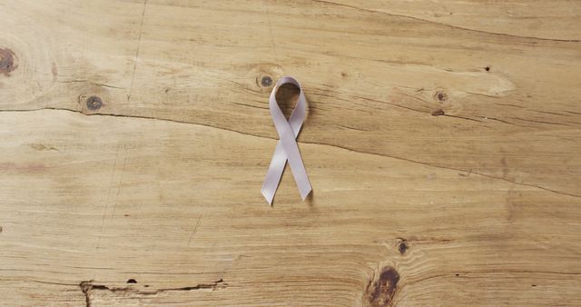 Lavender ribbon lying flat on a light wooden surface. This image can be used for articles or campaigns related to supporting health, awareness causes, or events. Ideal for websites, blogs, promotional materials, and social media posts highlighting awareness programs and support initiatives.
