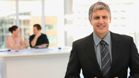 Confident Businessman with Team Collaborating in Background