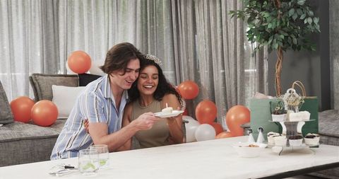 Multiracial Couple Celebrating Birthday with Cupcake in Living Room