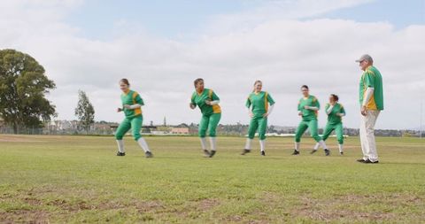Female softball team jogging with coach