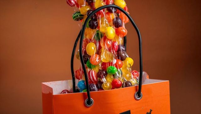 Colorful Lollipops Overflow Orange Gift Bag on Brown Background