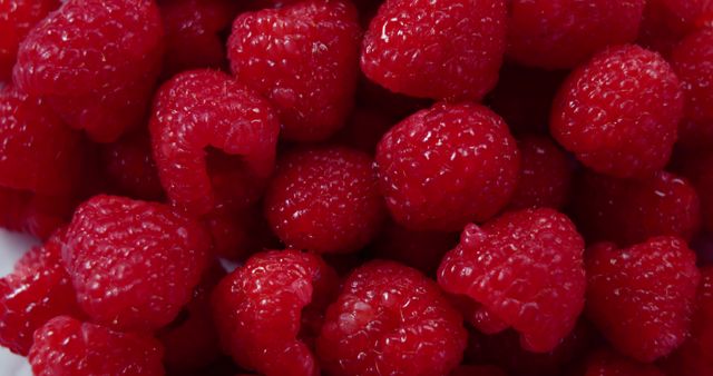 Brightly colored close-up of ripe raspberries. Perfect for healthy living, food blogs, recipes, nutrition magazines, or grocery store promotions.