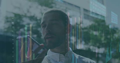 Executive speaking on smartphone with financial charts reflecting on office glass