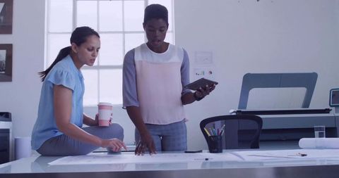 Two women collaborating over architectural plans in modern creative studio