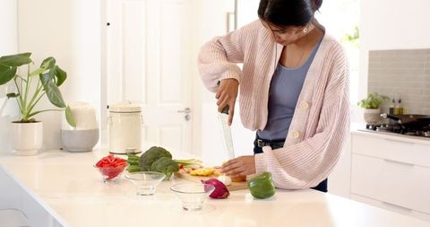Woman Chopping Fresh Bell Peppers in Modern Kitchen