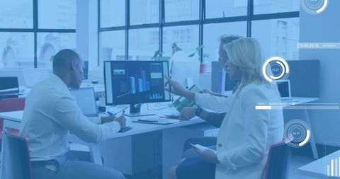 Team reviewing analytics dashboard, pointing at monitor in modern open-plan office