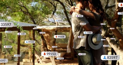 Romantic couple embracing with floating digital icons outdoors