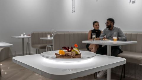 Glowing plated chocolate tart on illuminated white table in minimalist chic cafe interior