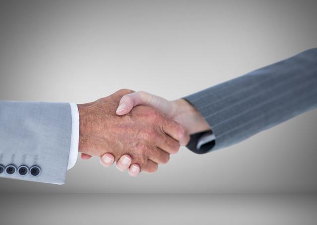 Handshake between business people on grey background symbolizes professional agreement, partnership, and collaboration. Suitable for illustrating concepts related to business deals, agreements, corporate partnerships, networking events, and professional greetings. Ideal for use in marketing materials, corporate presentations, agreement documentation, team-building content, and business websites.