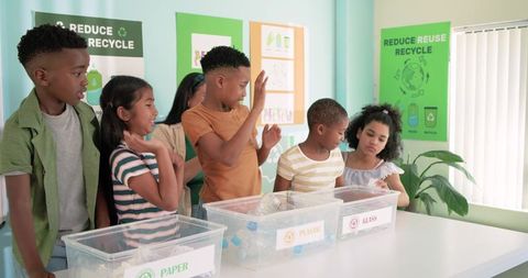 Diverse children sorting paper, plastic, glass recyclables in school environmental lesson