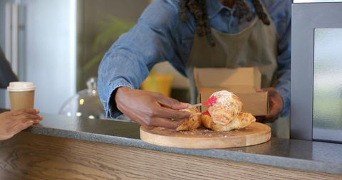 African american barista glazing fresh croissants at rustic cafe counter with pastry brush