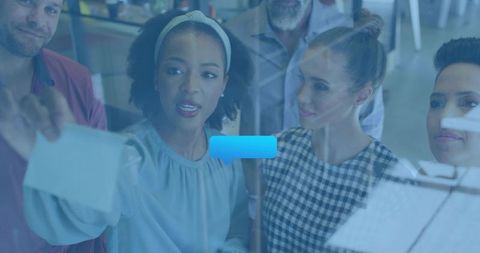 Woman leading team brainstorming on glass wall sticky notes planning session