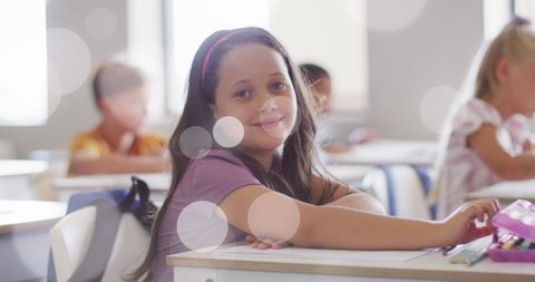 Smiling Biracial Schoolgirl Sitting at Classroom Desk - Download Free Stock Images Pikwizard.com