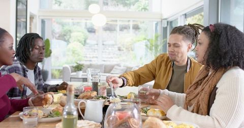 Multiracial Friends Sharing Brunch at Sunlit Modern Dining Table, Casual Weekend Gathering