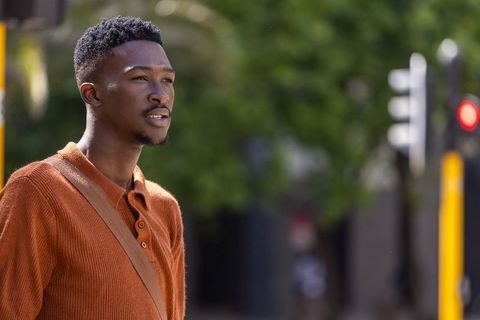 African american man wearing rust knit polo and tan crossbody bag standing on urban street