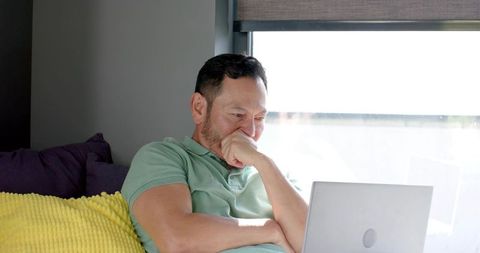 Man Relaxing on Sofa Using Laptop in Modern Living Room