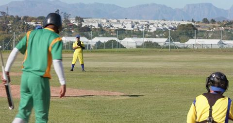 Veteran players batting and fielding on suburban cricket ground with mountain backdrop